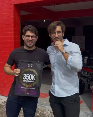 Parceiro da KP segurando a Placa de Faturamento 350K em frente à loja